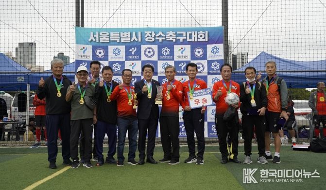지난 10월 11일과 12일, 성동구 살곶이체육공원 축구장에서 열린 ‘서울시 7080 장수축구대회’에 참석한 김용호 서울시의원(왼쪽 여섯 번째)이 70대B조에서 우승한 용산구 70대 장수축구단에게 우승컵과 트로피를 시상한 후 기념촬영을 하고 있다.